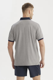 Polera gris de hombre con cuello contraste azul oscuro lisa y detalle de logo pequeño en el pecho estilo casual