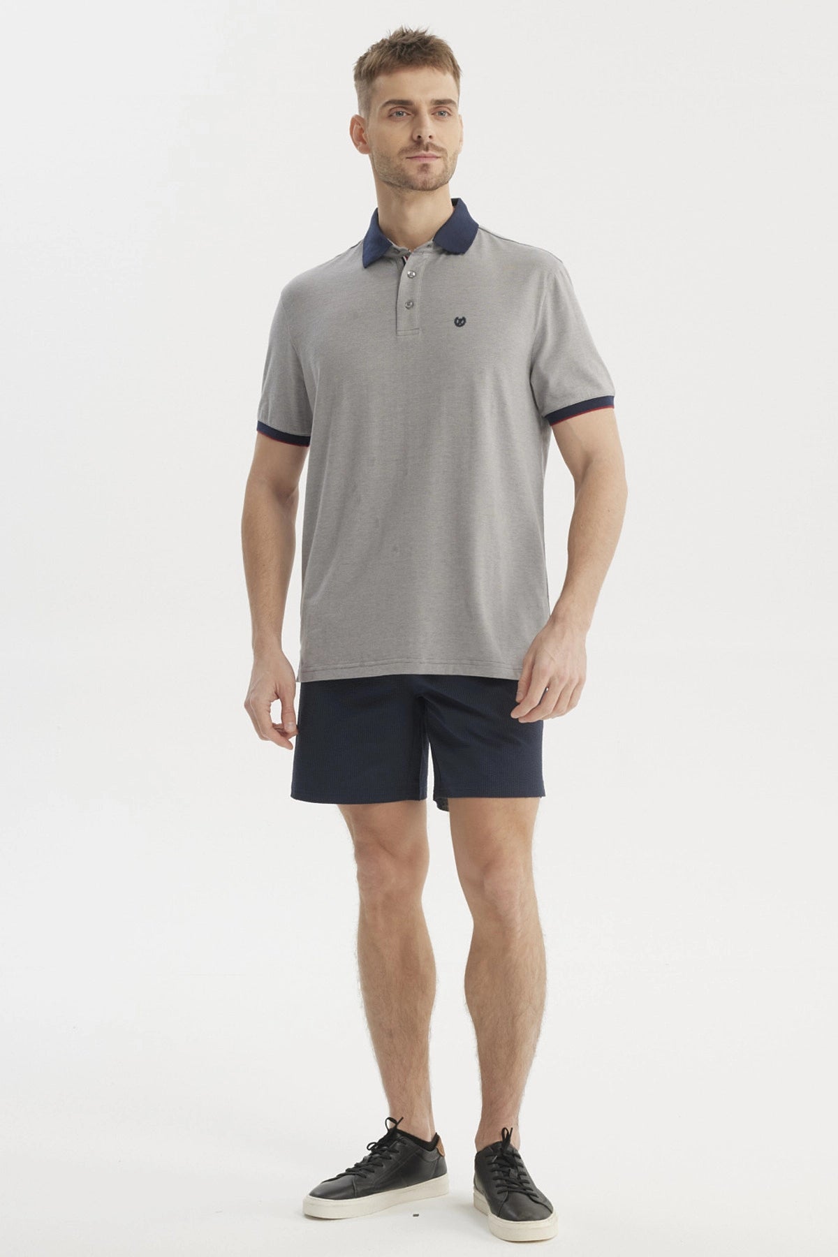 Polera gris de hombre con cuello contraste azul oscuro lisa y detalle de logo pequeño en el pecho estilo casual