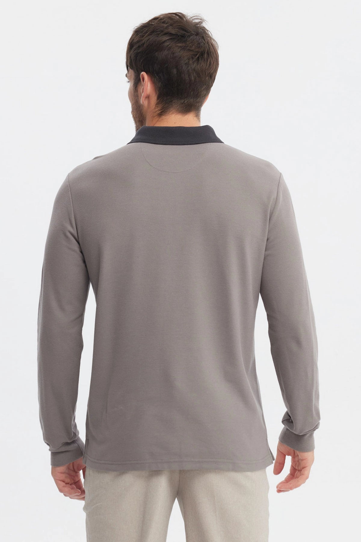 Polera gris de hombre con cuello contraste negro manga larga lisa ajuste relajado y logo pequeño en el pecho