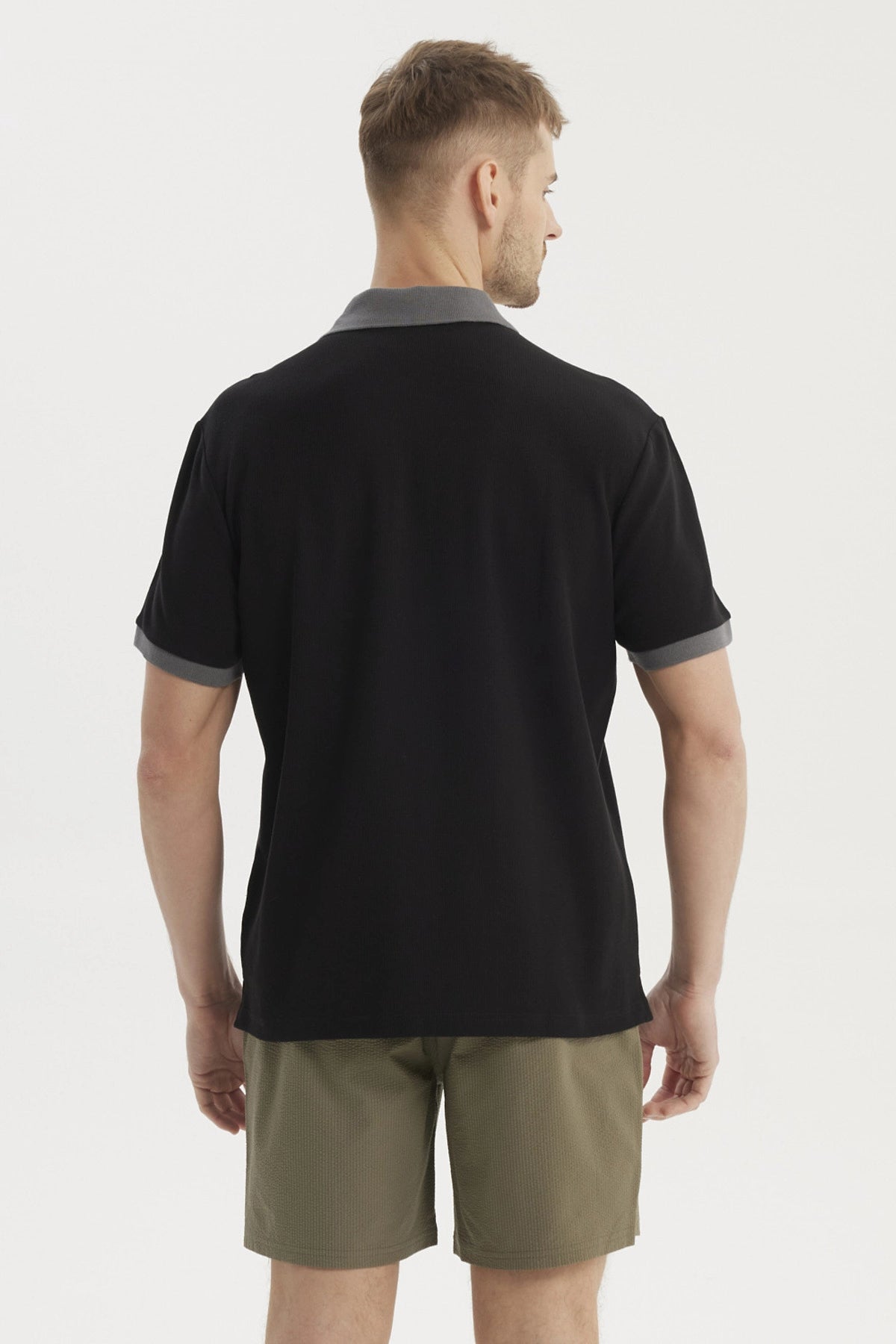 Polera negra de hombre con botones y cuello gris estilo pique sin estampa visible