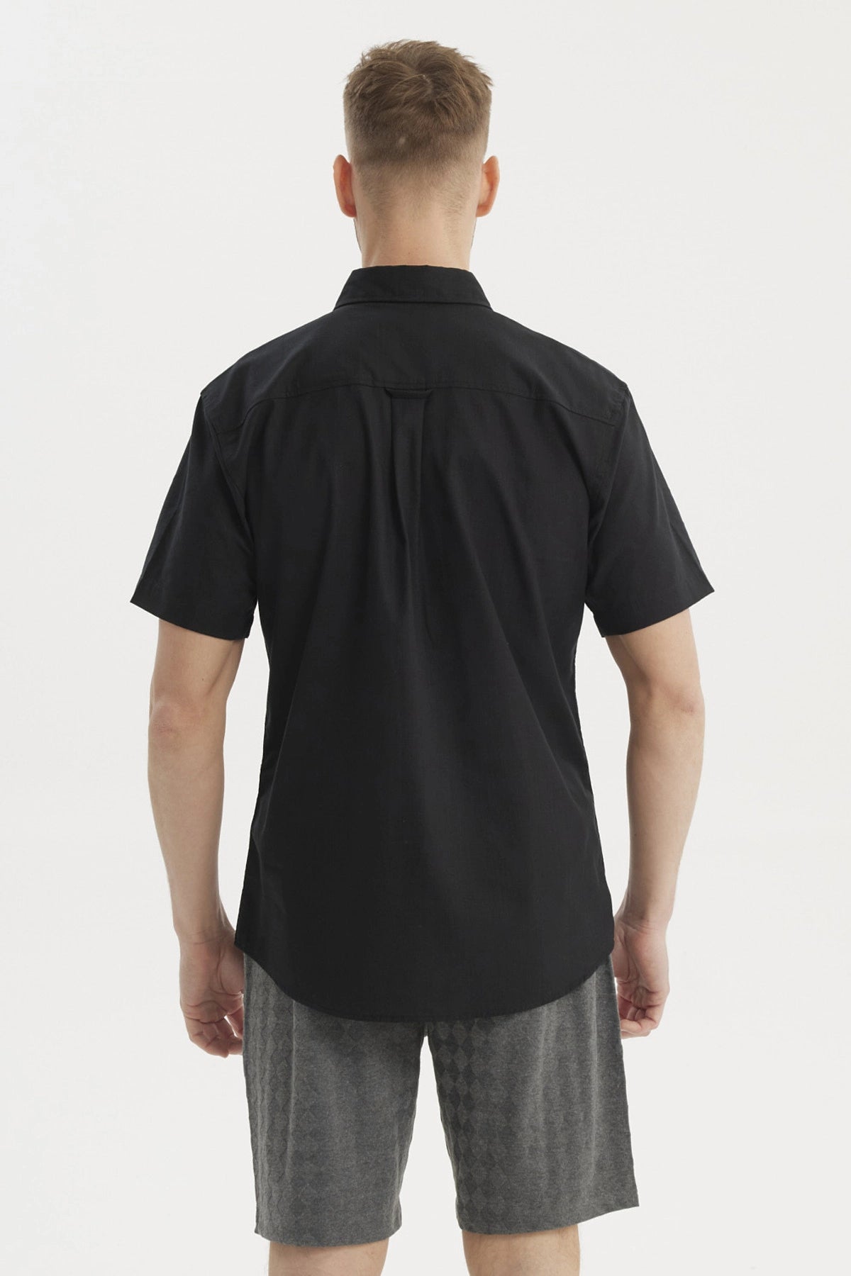 Camisa negra de hombre con cuello camisero manga corta y un bolsillo liso a la altura del pecho