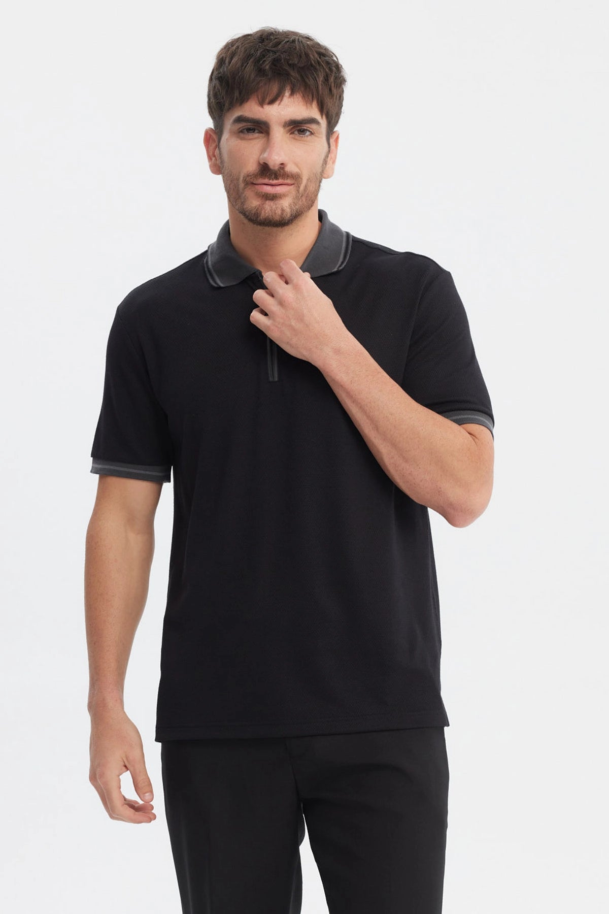 Polera negra de hombre con textura y cierre tipo polo sin estampa visible con ribetes grises en cuello y mangas