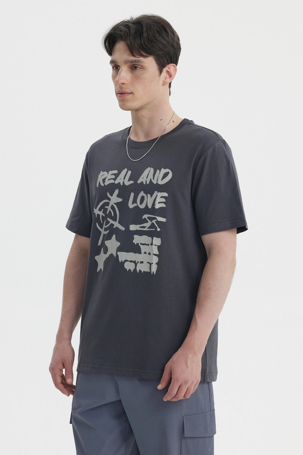 Polera oversize marengo con estampa grande al frente con texto Real And Love y símbolos abstractos en blanco
