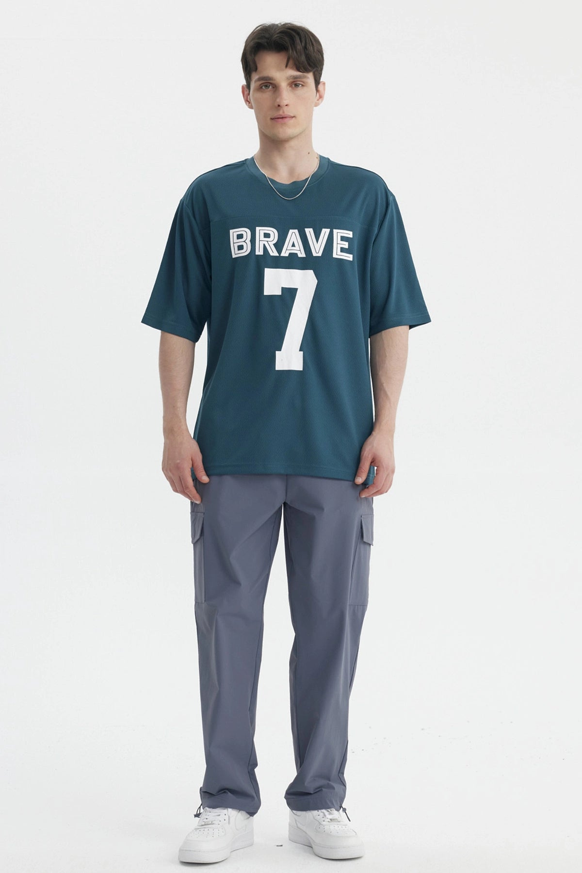 Polera oversize petróleo con texto BRAVE 7 en blanco centrado al frente estilo deportivo y casual