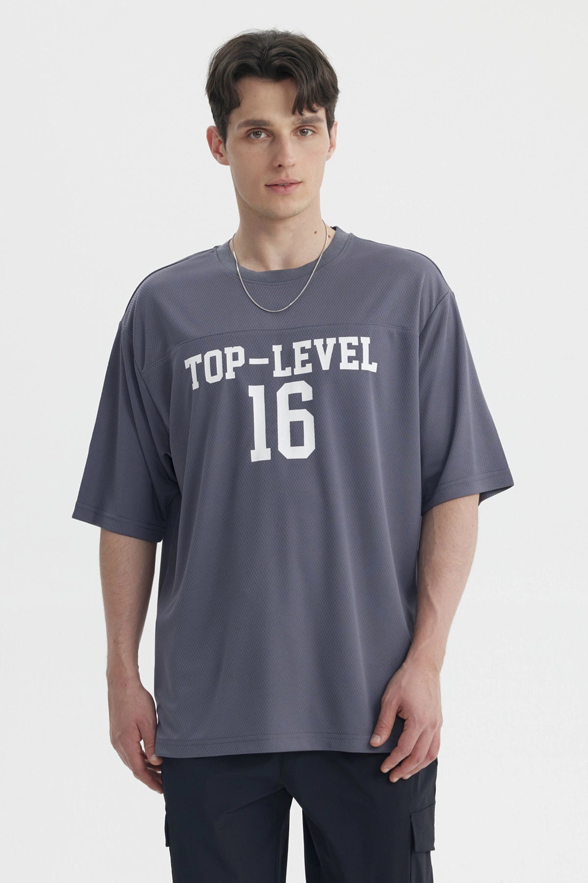 Polera oversize gris de hombre con texto Top-Level 16 en el pecho estilo deportivo casual sin estampa adicional