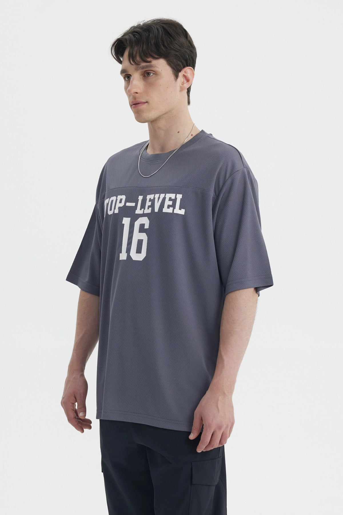 Polera oversize gris de hombre con texto Top-Level 16 en el pecho estilo deportivo casual sin estampa adicional