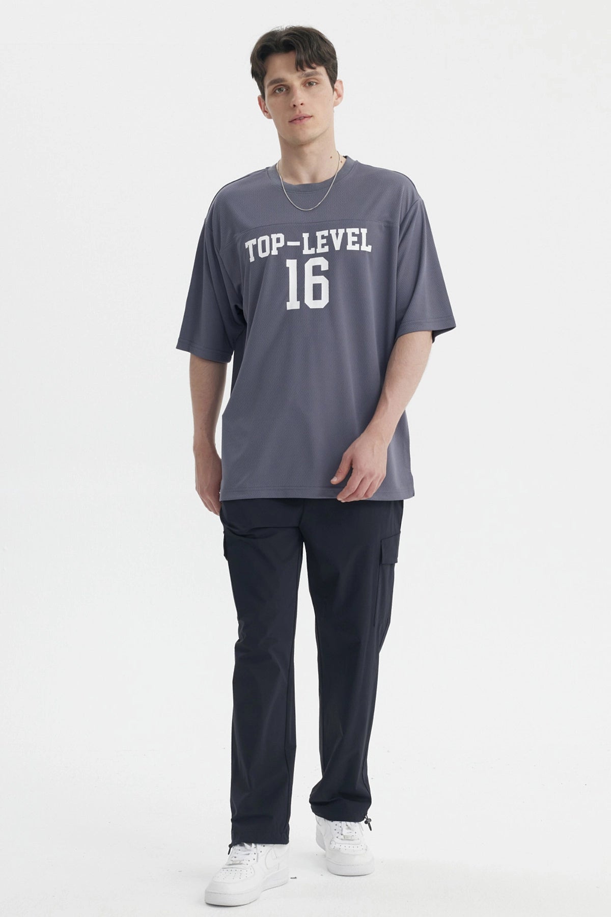 Polera oversize gris de hombre con texto Top-Level 16 en el pecho estilo deportivo casual sin estampa adicional