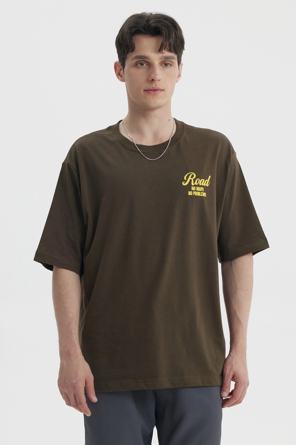 Polera oversize verde militar con estampado amarillo en el pecho que dice Road No Maps No Problems estilo casual relajado