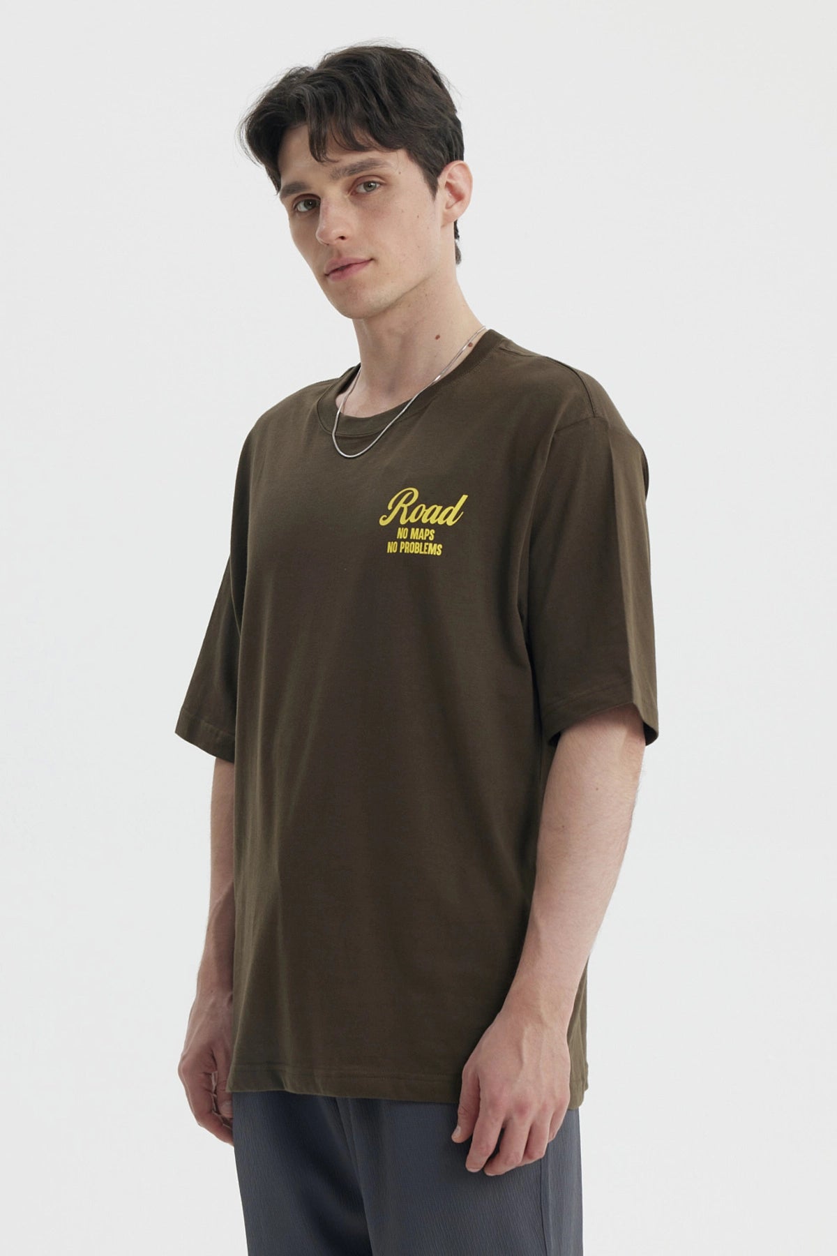 Polera oversize verde militar con estampado amarillo en el pecho que dice Road No Maps No Problems estilo casual relajado