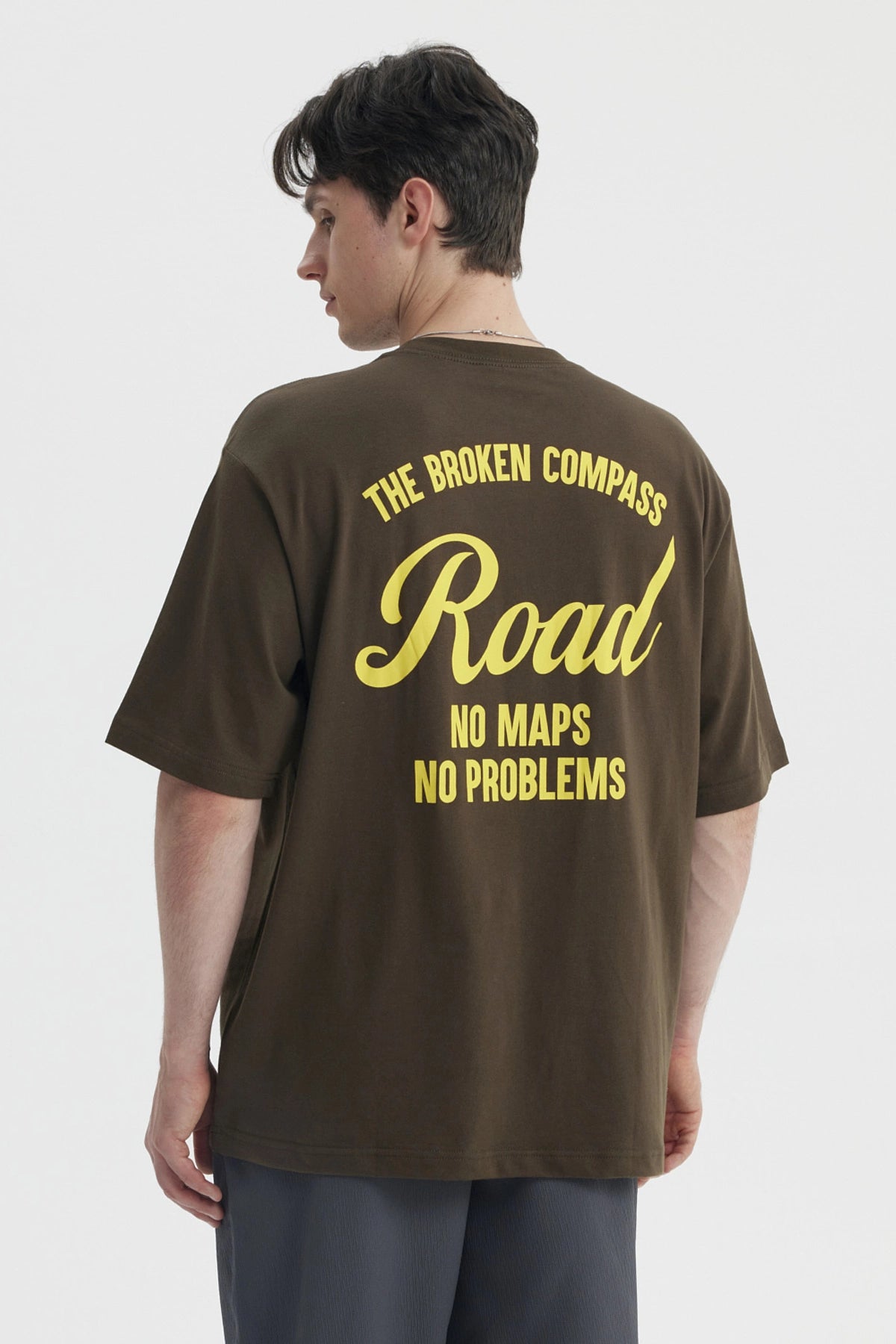 Polera oversize verde militar con estampado amarillo en el pecho que dice Road No Maps No Problems estilo casual relajado