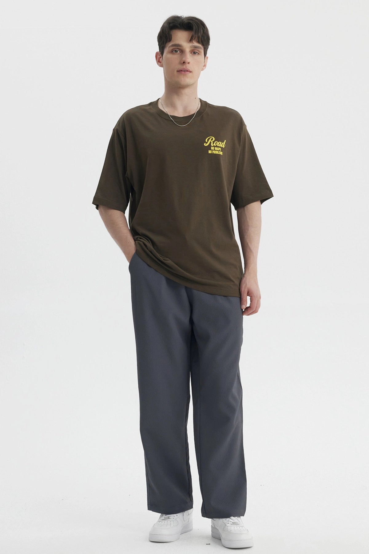 Polera oversize verde militar con estampado amarillo en el pecho que dice Road No Maps No Problems estilo casual relajado