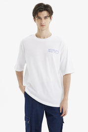 Polera hombre slim blanca con texto azul Meaningful Global Travel en el pecho estilo minimalista urbana y cómoda