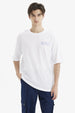 Polera hombre slim blanca con texto azul Meaningful Global Travel en el pecho estilo minimalista urbana y cómoda