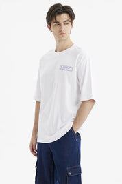 Polera hombre slim blanca con texto azul Meaningful Global Travel en el pecho estilo minimalista urbana y cómoda