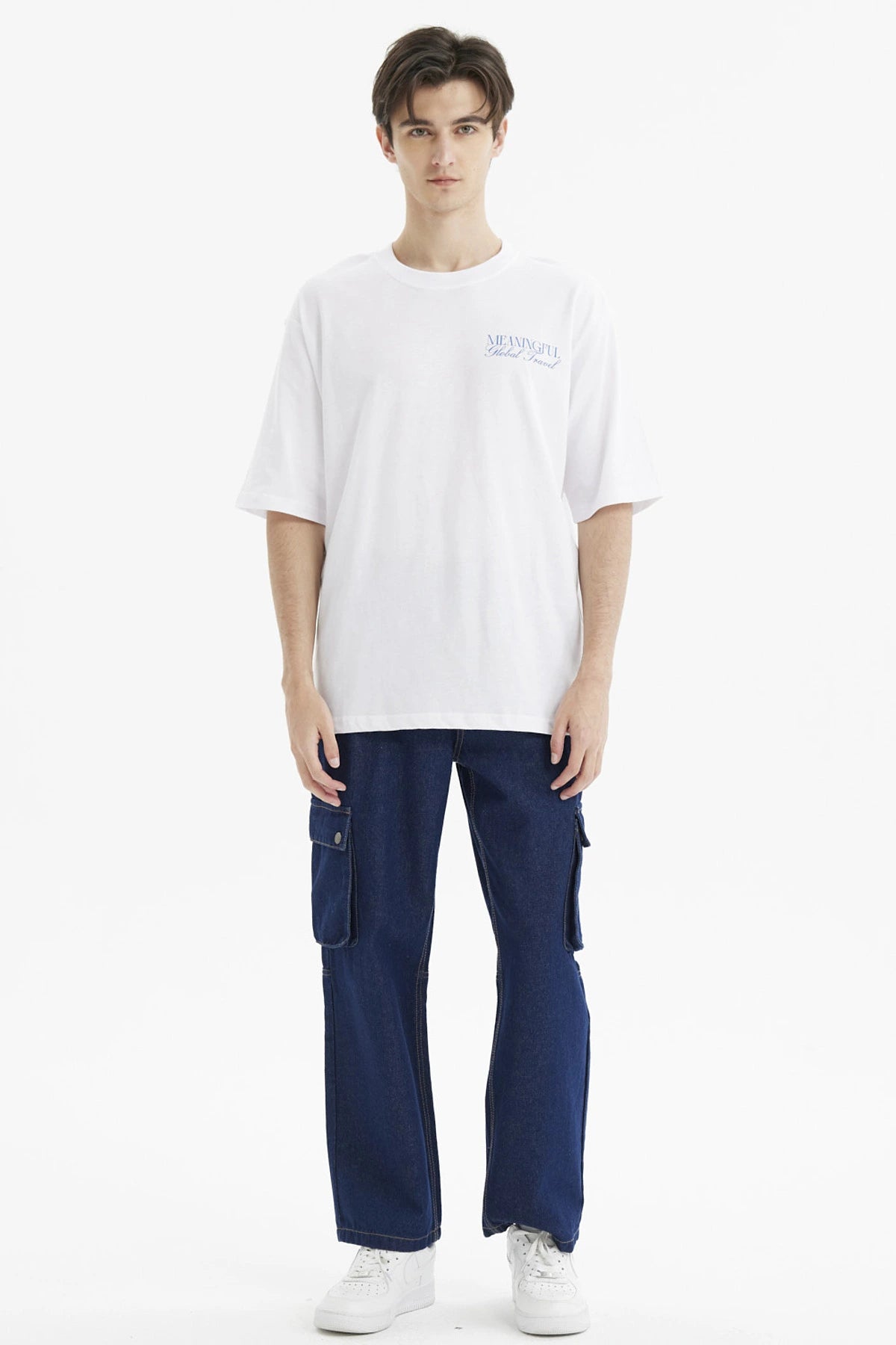Polera hombre slim blanca con texto azul Meaningful Global Travel en el pecho estilo minimalista urbana y cómoda