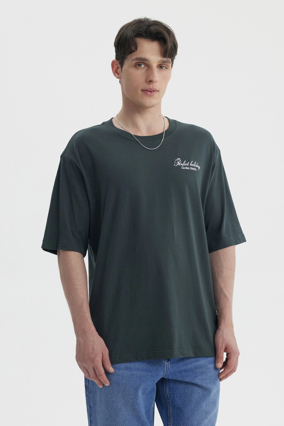 Polera hombre slim verde con estampa pequeña en el pecho que dice Perfect holiday Global travel en blanco casual y cómoda