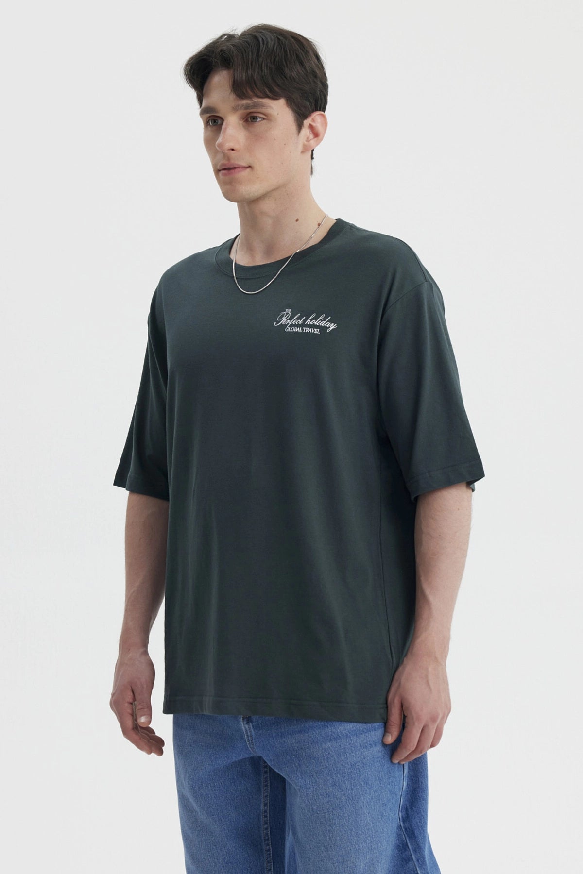 Polera hombre slim verde con estampa pequeña en el pecho que dice Perfect holiday Global travel en blanco casual y cómoda