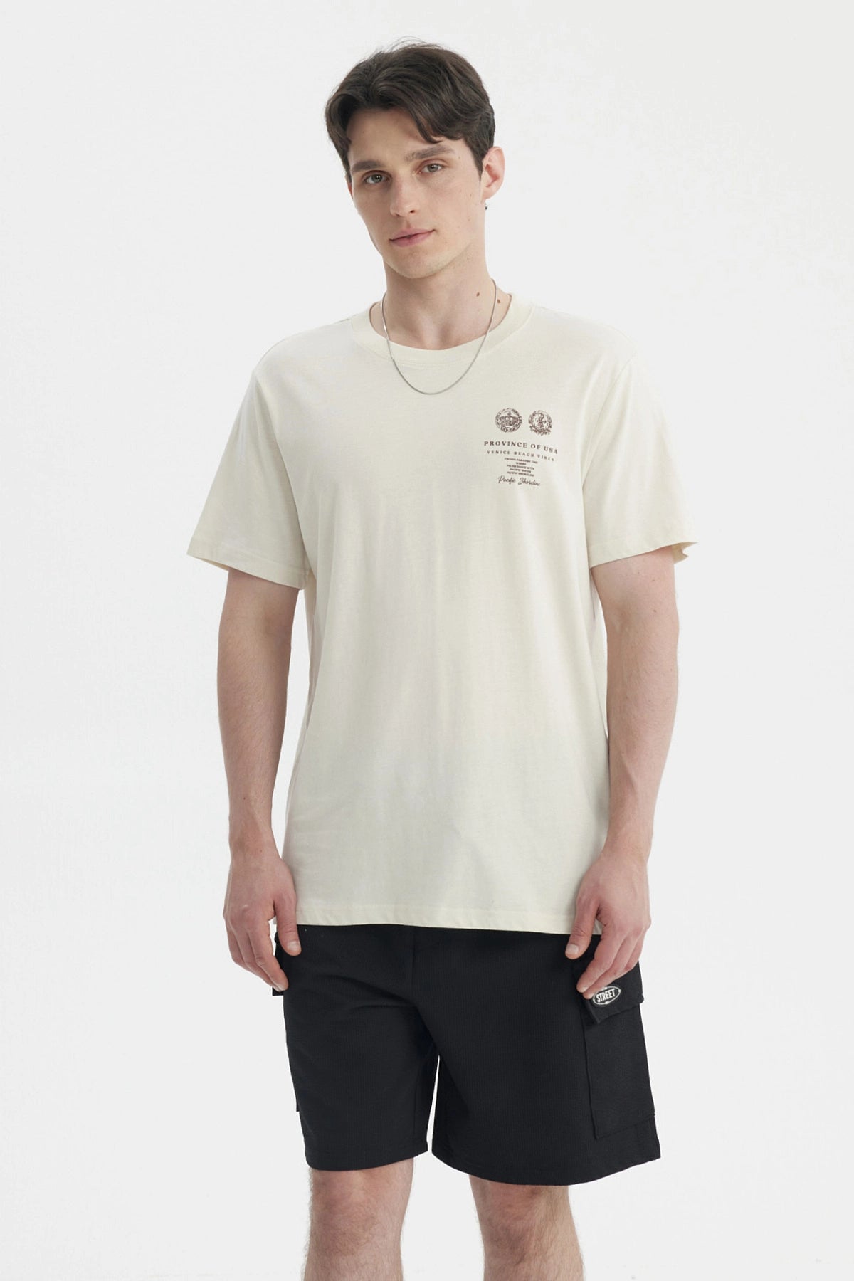 Polera oversize beige para hombre con estampado gráfico pequeño en el pecho a la izquierda