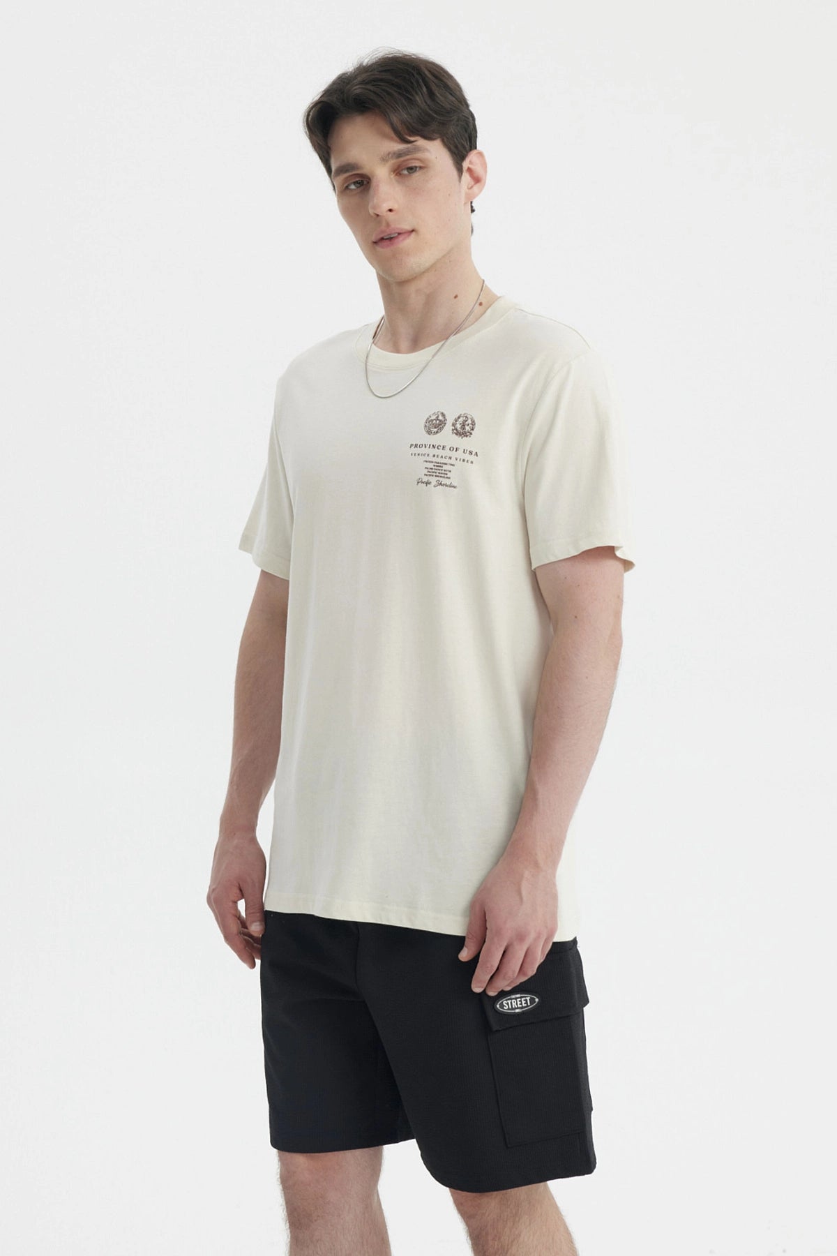 Polera oversize beige para hombre con estampado gráfico pequeño en el pecho a la izquierda