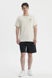 Polera oversize beige para hombre con estampado gráfico pequeño en el pecho a la izquierda