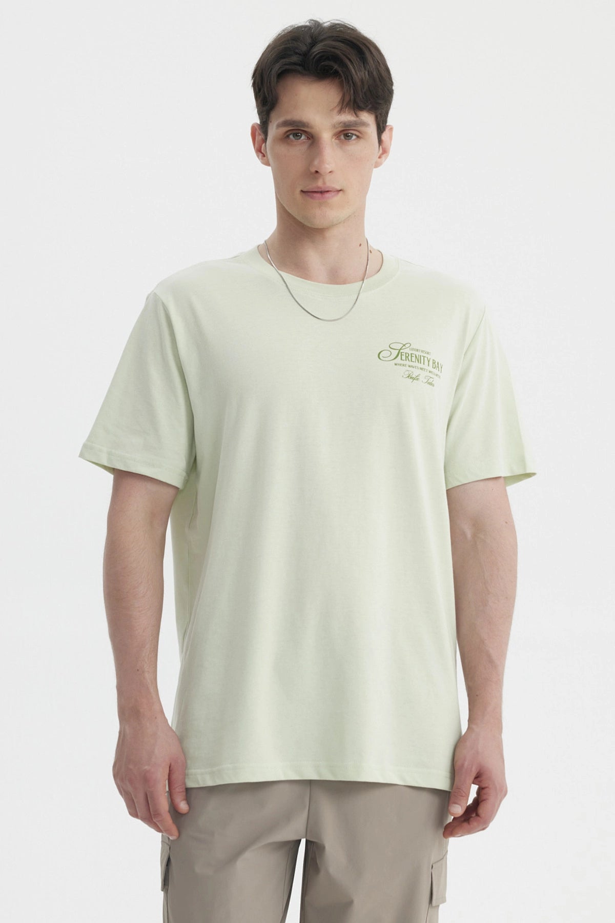 Polera oversize verde claro hombre con texto Serenity Bay en el pecho diseño minimalista y estilo casual relajado