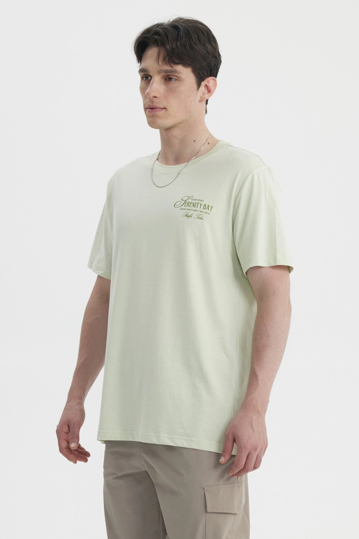 Polera oversize verde claro hombre con texto Serenity Bay en el pecho diseño minimalista y estilo casual relajado