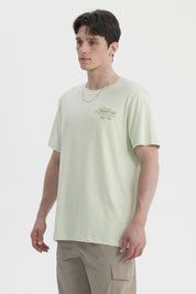 Polera oversize verde claro hombre con texto Serenity Bay en el pecho diseño minimalista y estilo casual relajado
