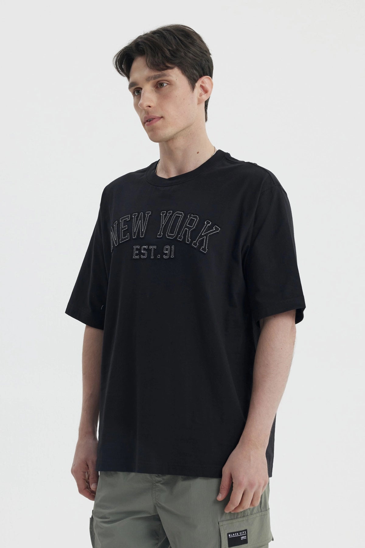 Polera negra de hombre con corte slim y estampa New York Est 91 en el pecho estilo urbano y letras grandes
