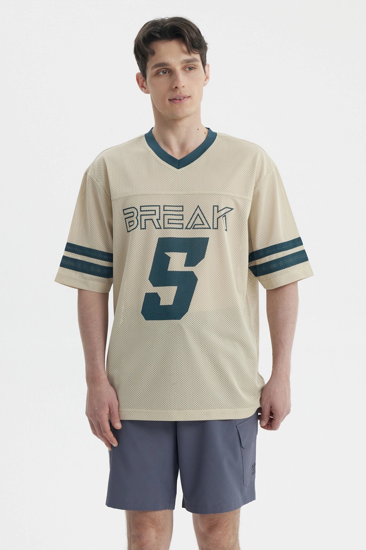 Polera oversize beige de hombre con cuello en V y mangas cortas lleva estampado Break y número 5 en el frente