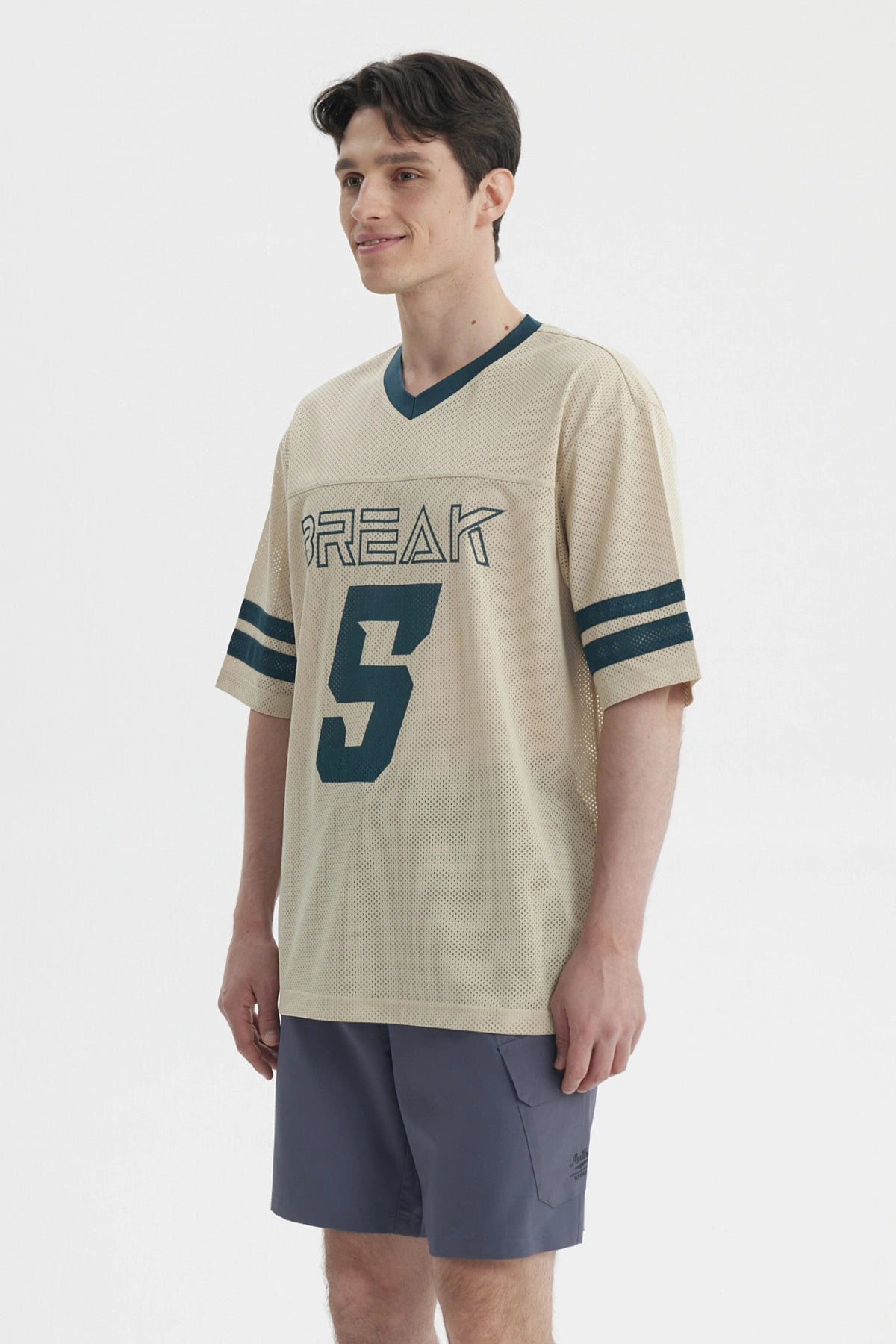 Polera oversize beige de hombre con cuello en V y mangas cortas lleva estampado Break y número 5 en el frente