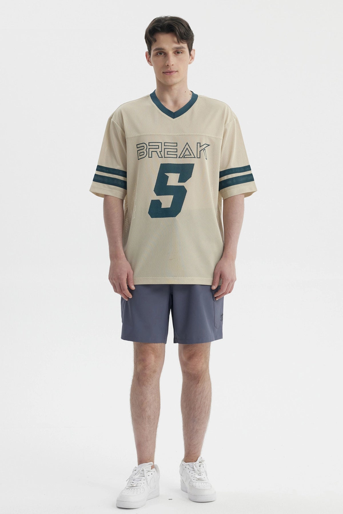 Polera oversize beige de hombre con cuello en V y mangas cortas lleva estampado Break y número 5 en el frente