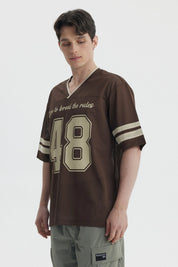 Polera oversize chocolate de hombre con texto Dare to break the rules y n
_x001B__x001B_mero 48 en el frente estilo deportivo