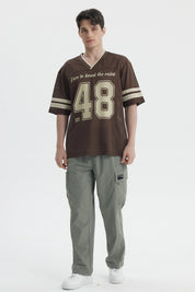 Polera oversize chocolate de hombre con texto Dare to break the rules y n
_x001B__x001B_mero 48 en el frente estilo deportivo