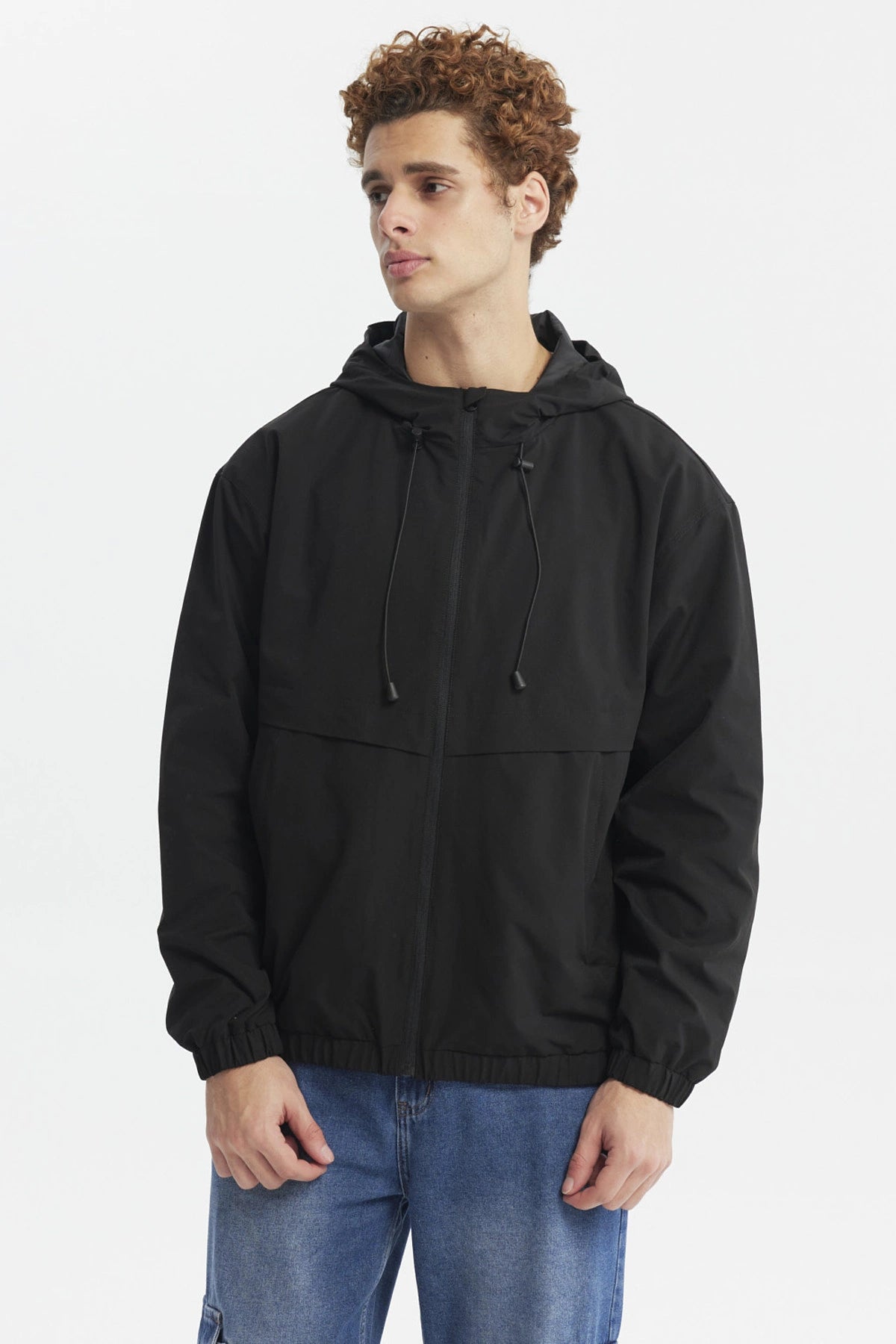 Chaqueta cortaviento negra de hombre con capucha y cordones ajustables diseño liso ideal para días ventosos