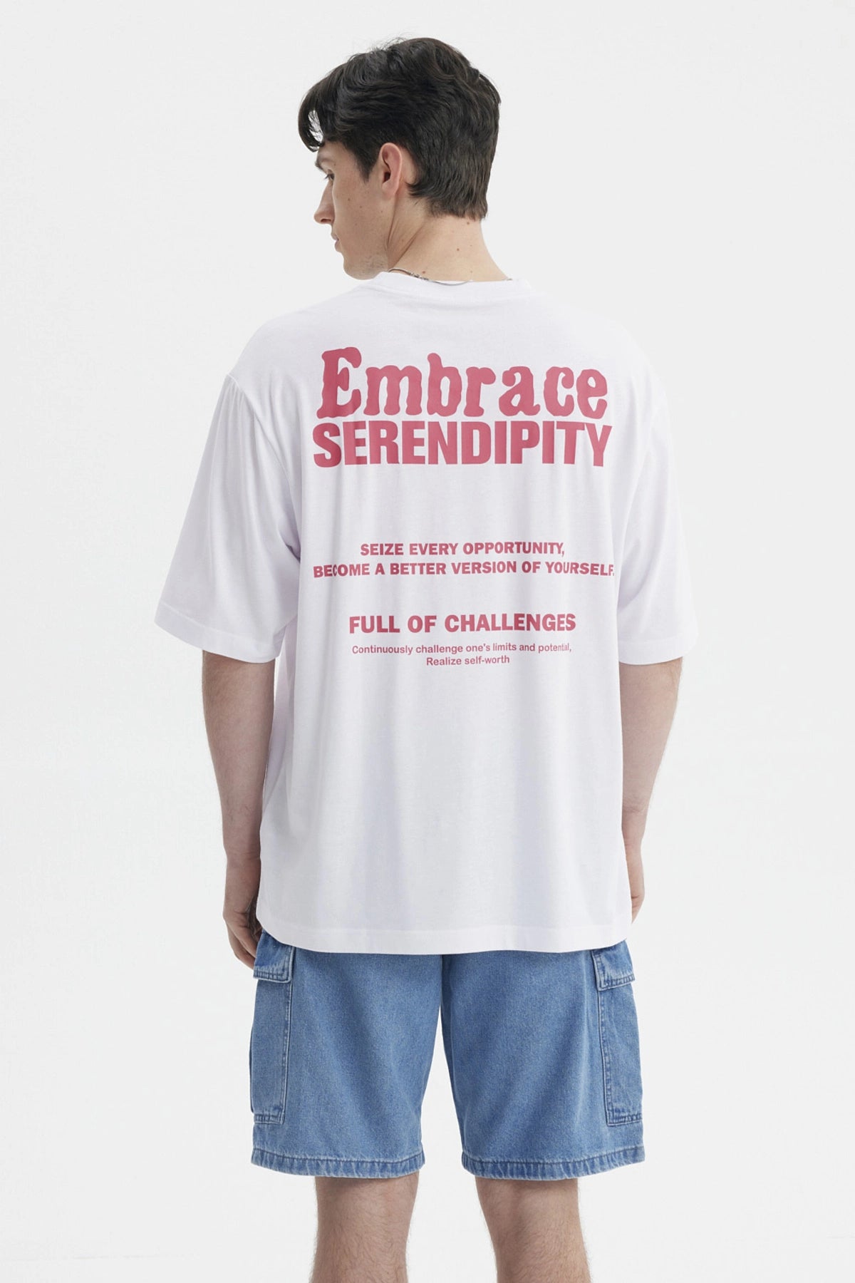 Polera blanca para hombre con texto rosado Embrace Serendipity en el pecho estilo casual y relajado sin estampa adicional