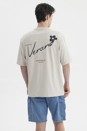 Polera beige de hombre con estampa pequeña en el pecho que dice Verano junto a una flor negra