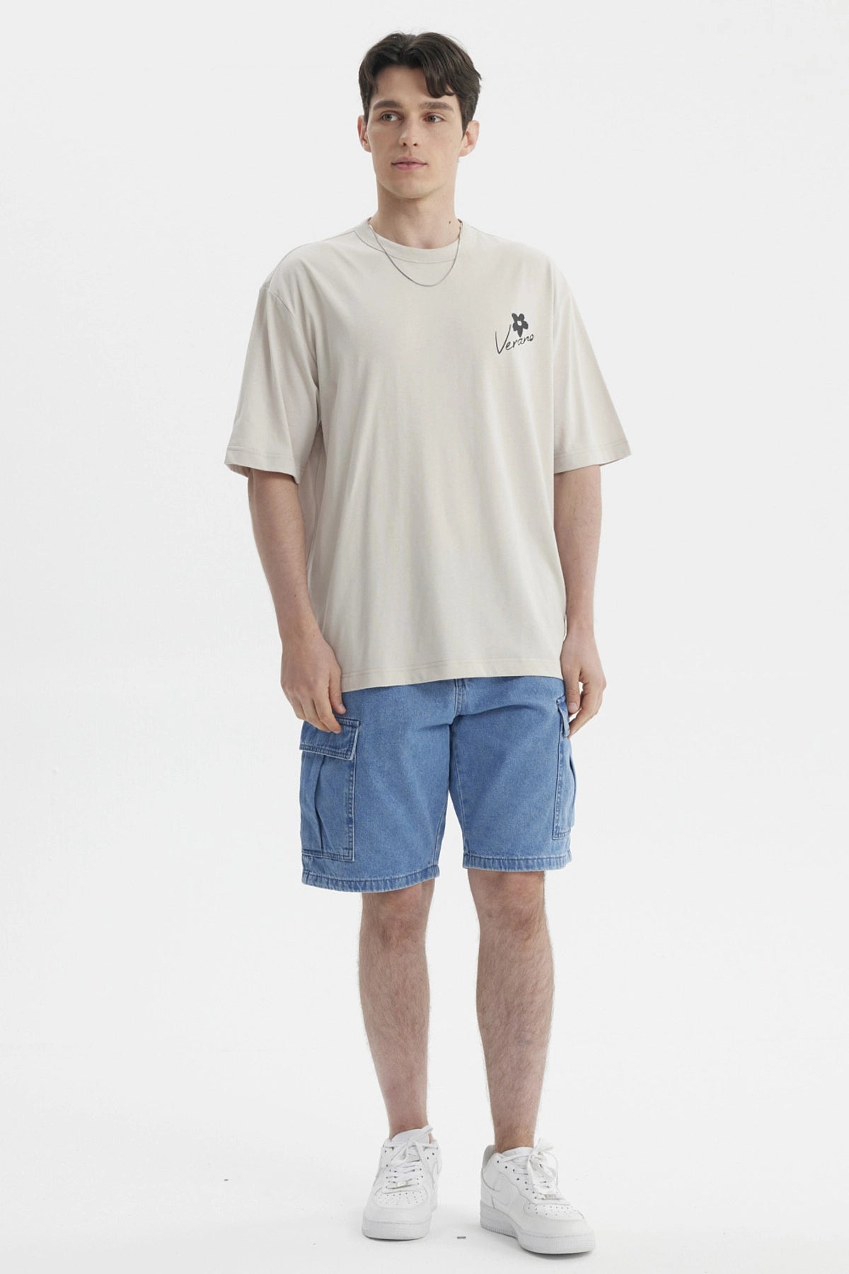 Polera beige de hombre con estampa pequeña en el pecho que dice Verano junto a una flor negra