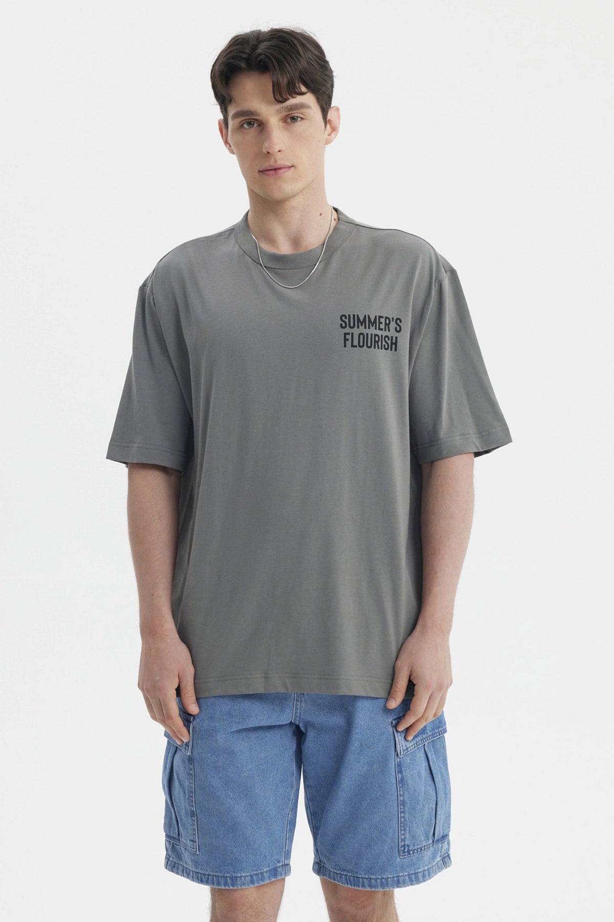 Polera gris para hombre con texto Summer's Flourish en el pecho estilo casual y corte relajado