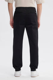 Pantalón jogger negro de hombre con cordón en la cintura diseño liso ajuste relajado y puños elásticos en tobillos