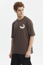 Polera oversize chocolate con estampado pequeño de media luna blanca en el pecho estilo minimalista