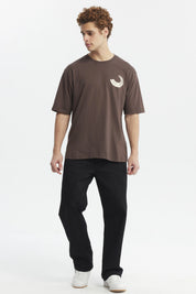 Polera oversize chocolate con estampado pequeño de media luna blanca en el pecho estilo minimalista