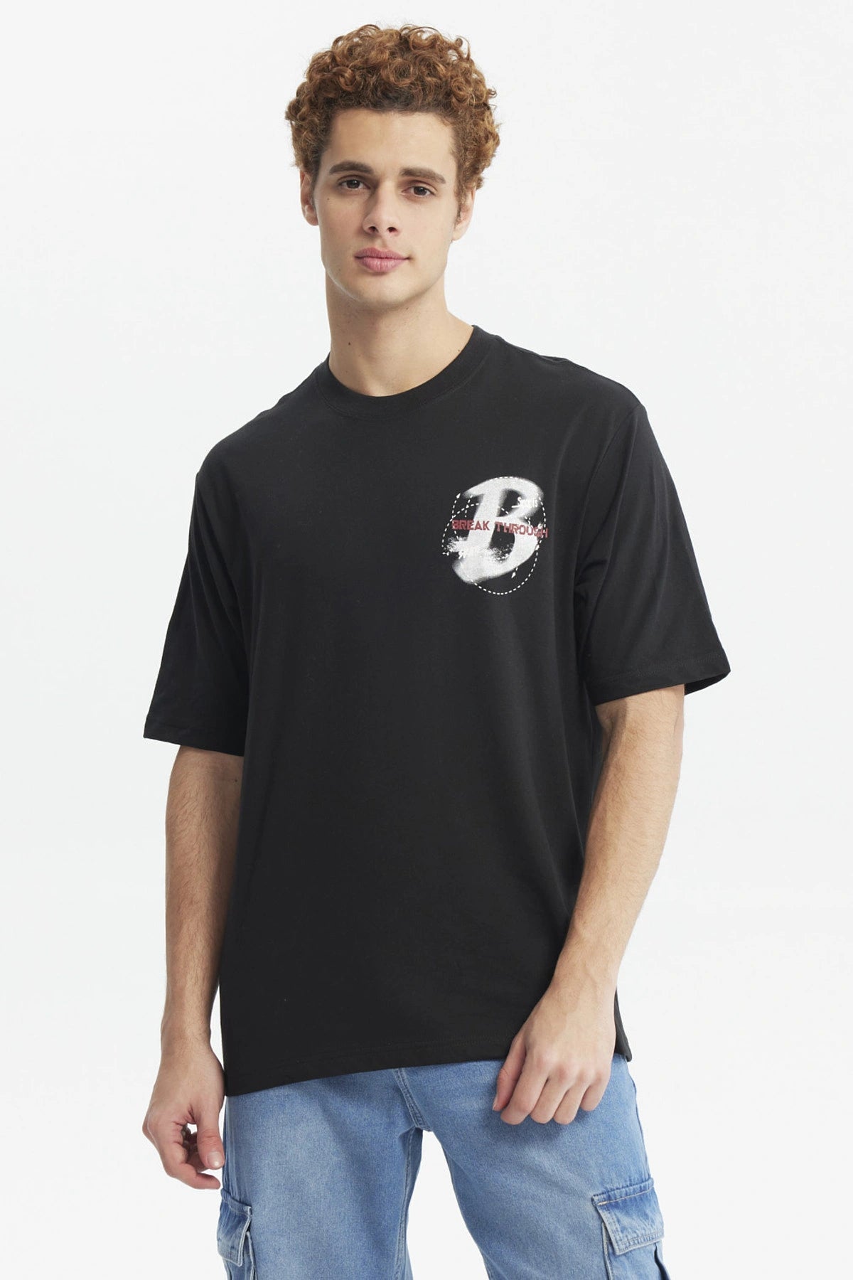 Polera oversize negra con estampado pequeño de letra H y texto Break Through en el pecho diseño moderno y minimalista