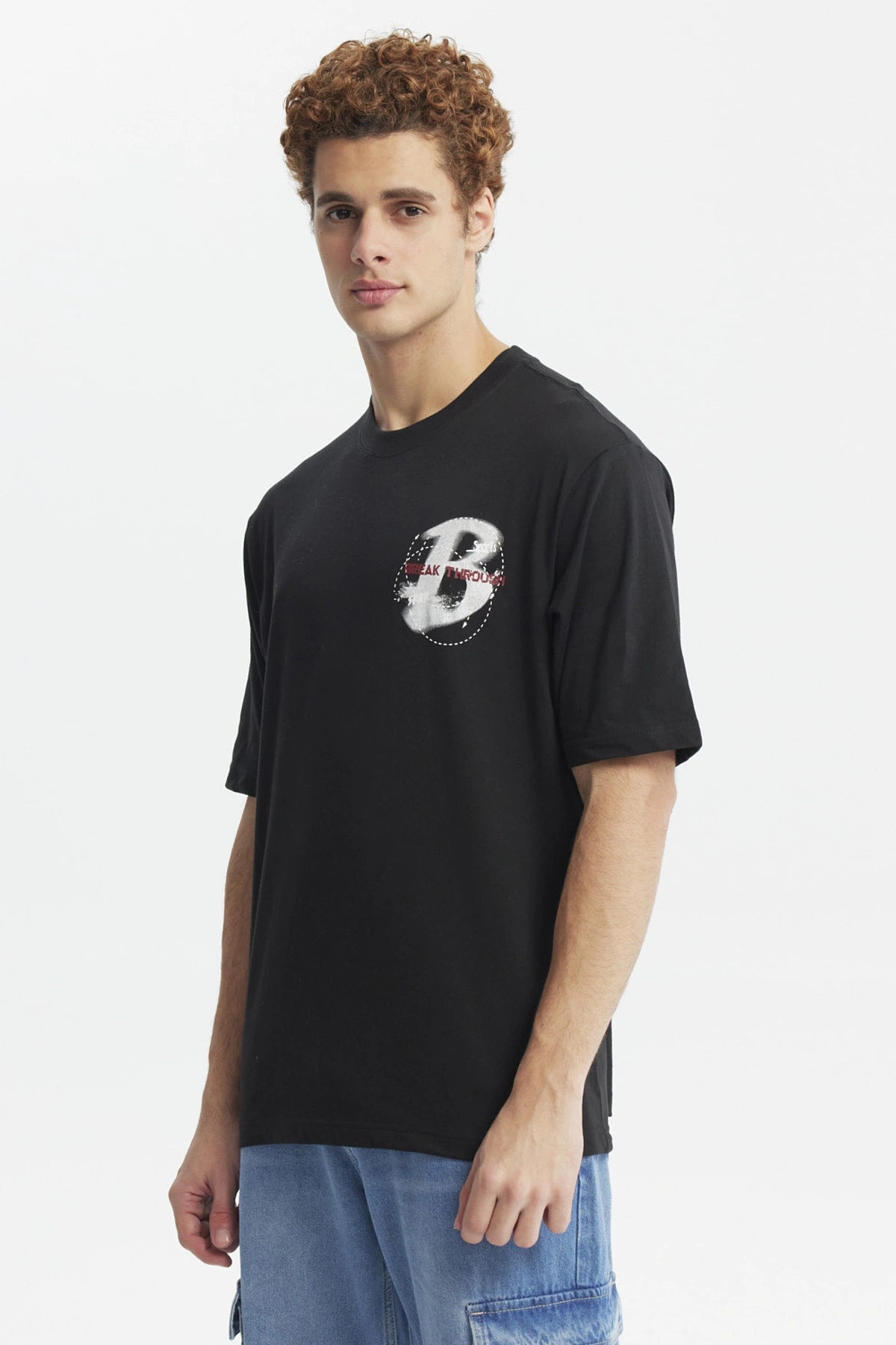 Polera oversize negra con estampado pequeño de letra H y texto Break Through en el pecho diseño moderno y minimalista