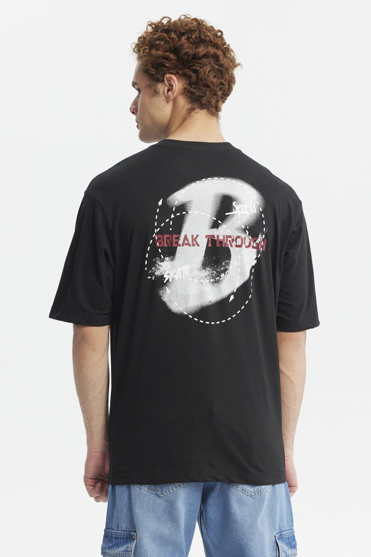 Polera oversize negra con estampado pequeño de letra H y texto Break Through en el pecho diseño moderno y minimalista