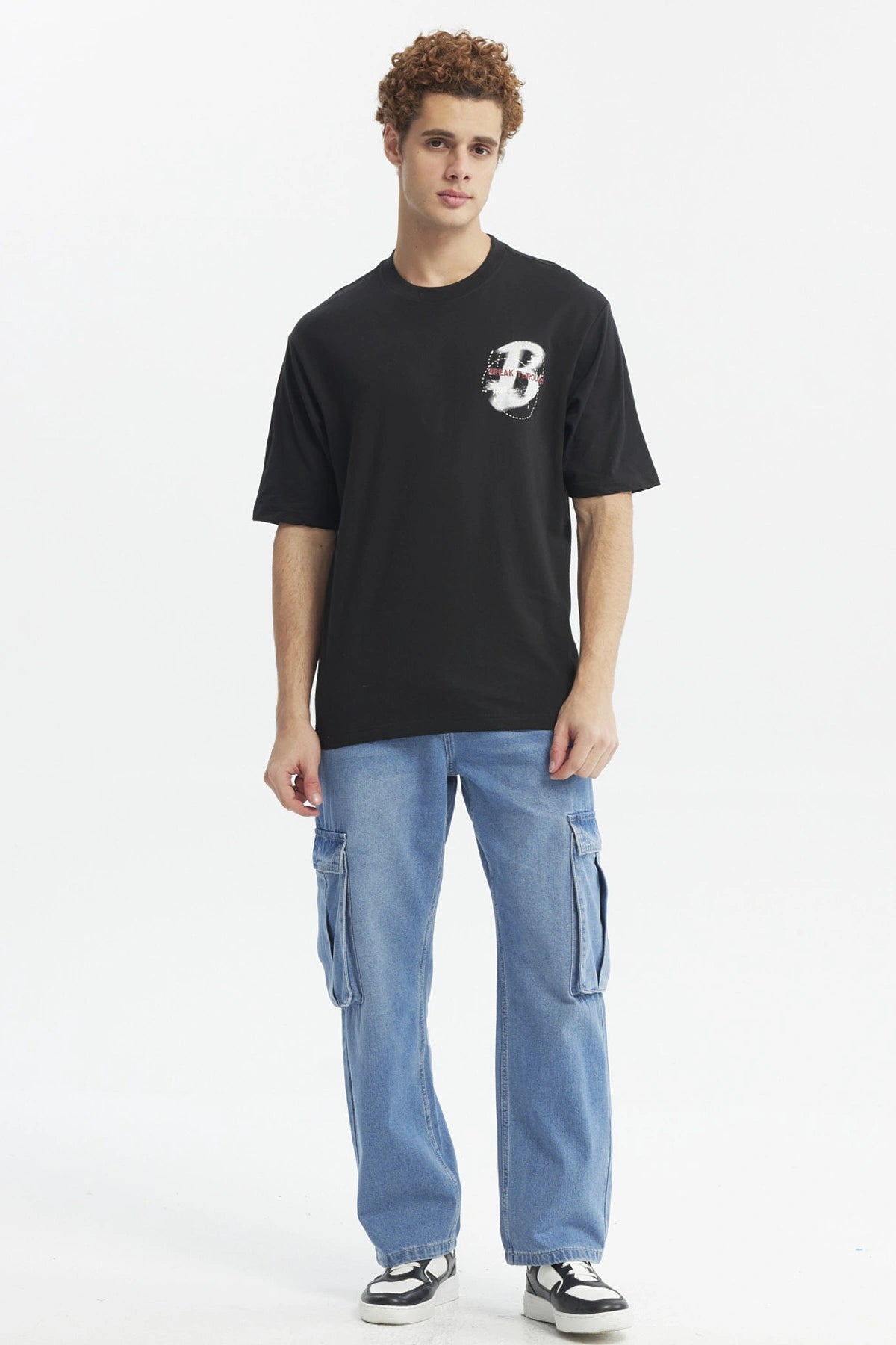 Polera oversize negra con estampado pequeño de letra H y texto Break Through en el pecho diseño moderno y minimalista