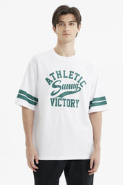 Polera oversize blanca para hombre con texto verde Athletic Sunny Victory al frente estilo casual y rayas en mangas