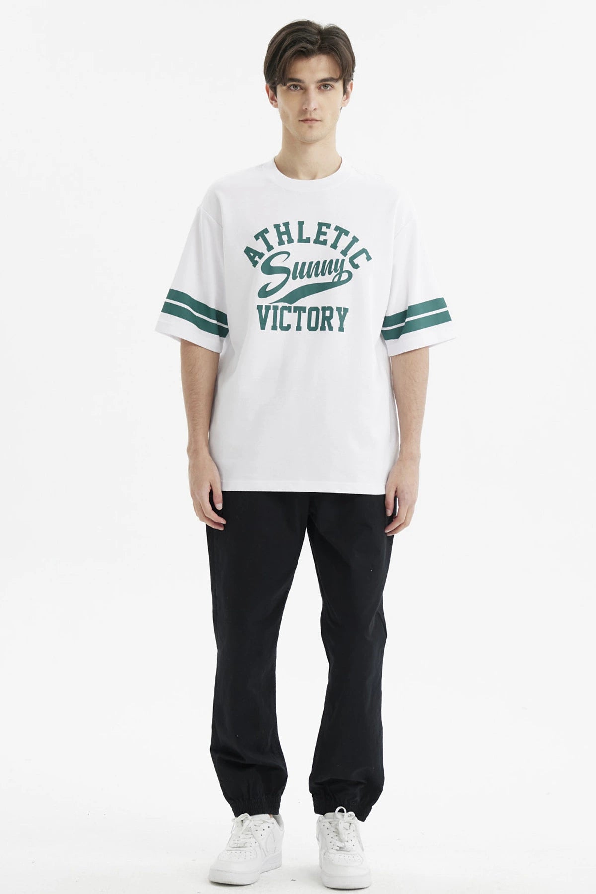 Polera oversize blanca para hombre con texto verde Athletic Sunny Victory al frente estilo casual y rayas en mangas