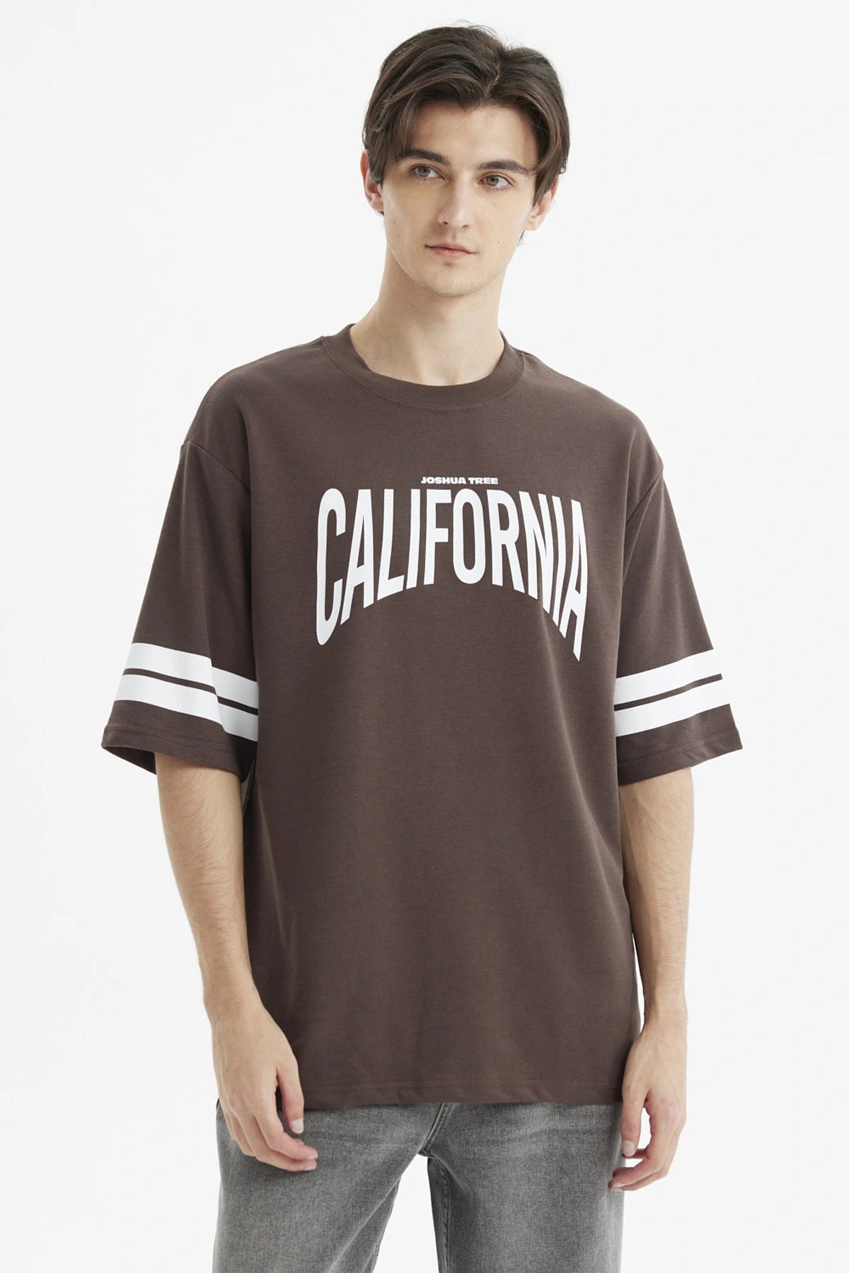 Polera oversize chocolate con estampado frontal California en blanco y rayas en las mangas estilo casual relajado