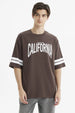 Polera oversize chocolate con estampado frontal California en blanco y rayas en las mangas estilo casual relajado