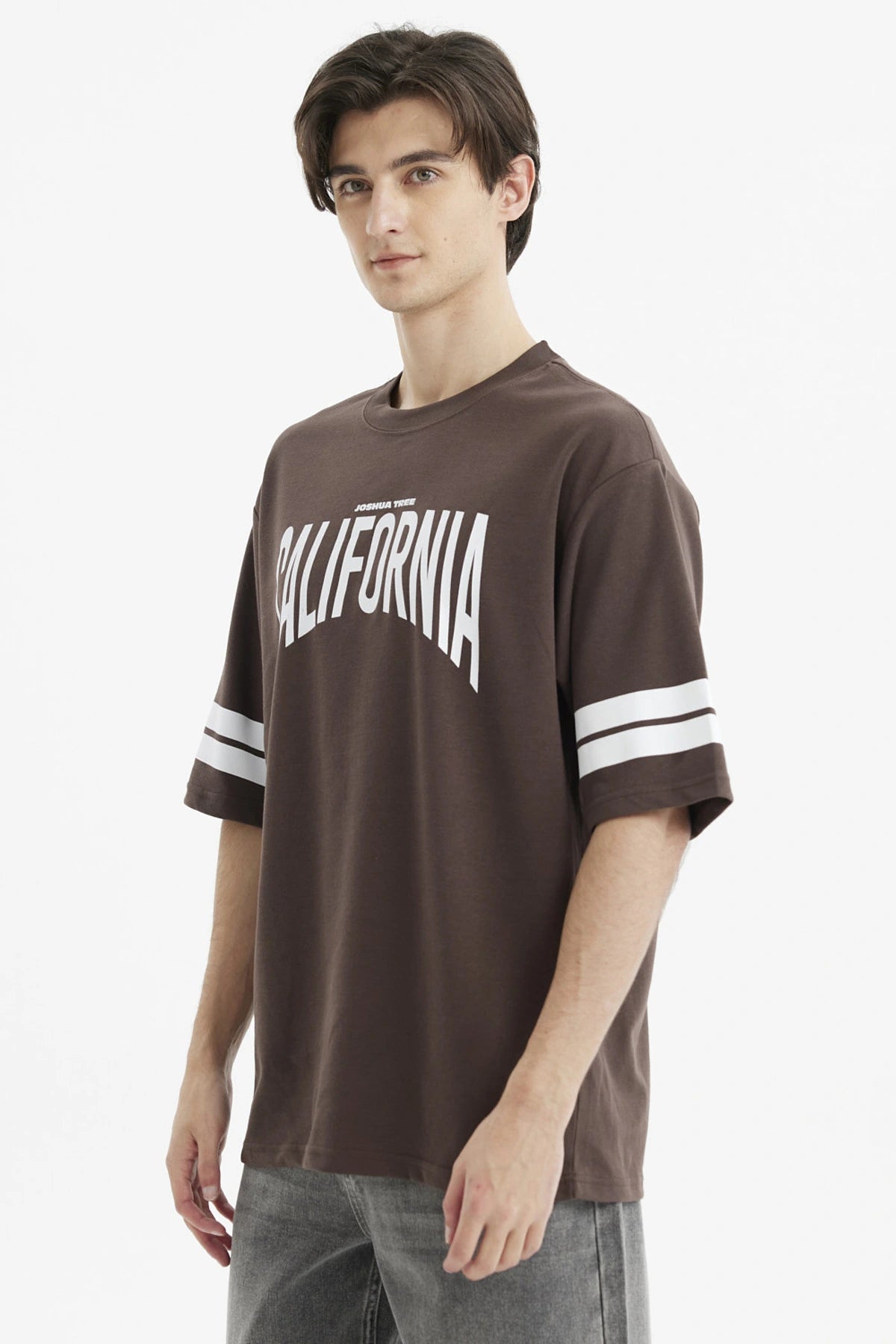 Polera oversize chocolate con estampado frontal California en blanco y rayas en las mangas estilo casual relajado
